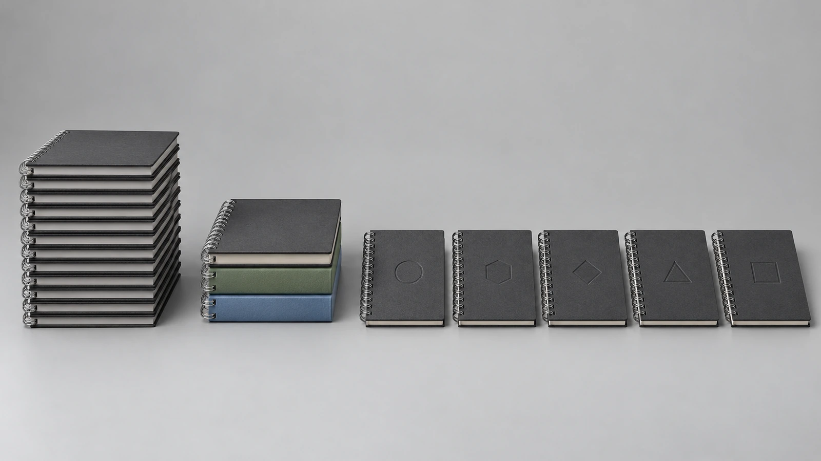 Três grupos de cadernos com encadernação wire-o mostrando personalização crescente: uma pilha idêntica, uma pilha dividida em três cores de capa e uma fileira de cadernos, cada um marcado com um pequeno emblema diferente