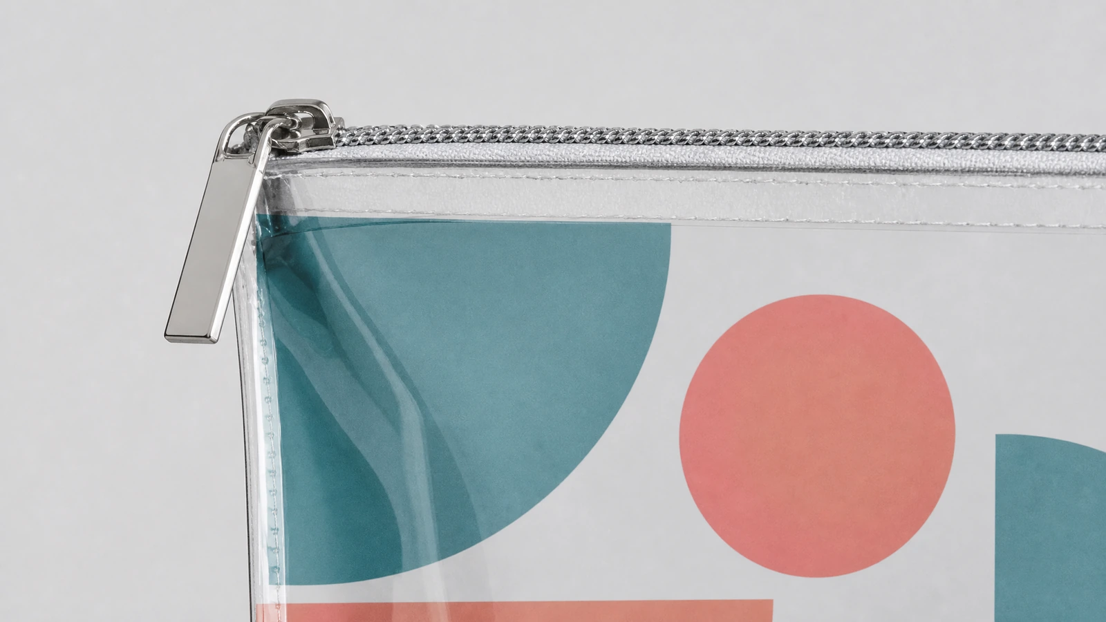 Detalhe do zíper e do canto da bolsa Close-up de um puxador de zíper prateado e do canto de uma bolsa transparente impressa