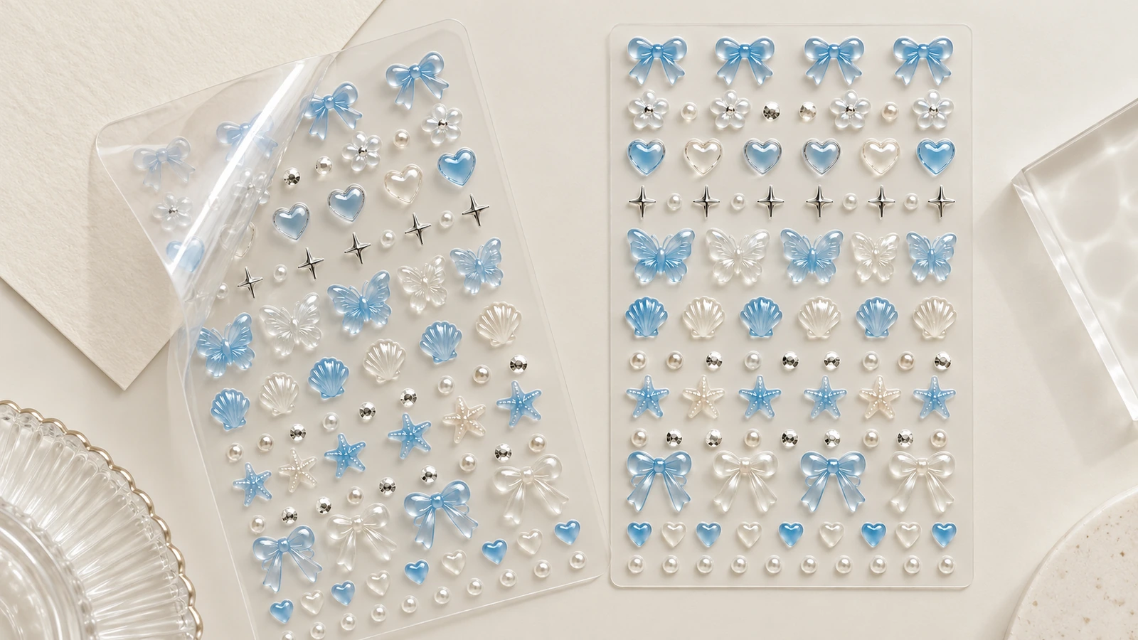 Duas folhas transparentes com laços, corações, conchas e decorações para unhas em tons azuis e perolados