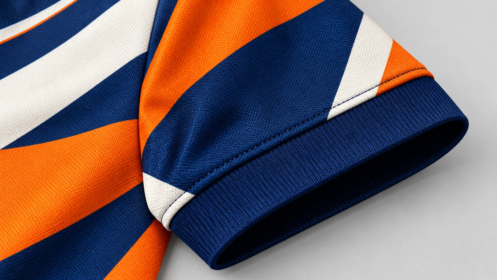 Close-up de uma manga estampada em laranja, azul-marinho e branco, com punho canelado azul-marinho