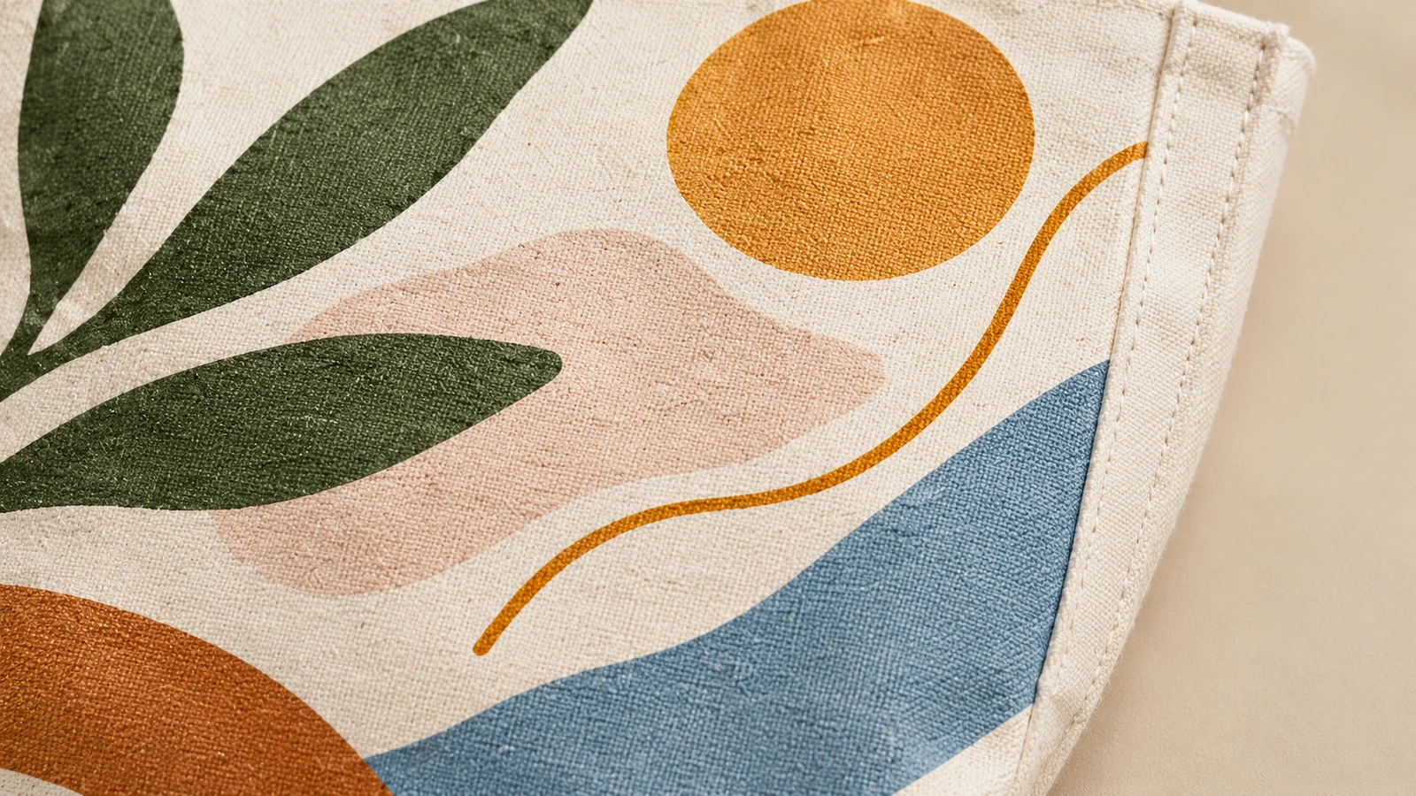 Close da arte de folhas e formas abstratas sobre tecido de algodão, ao lado de uma costura